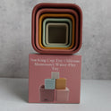 Five nested square Silicone Stacking Cups (Set of 5) balanced on top of their square packaging box.
