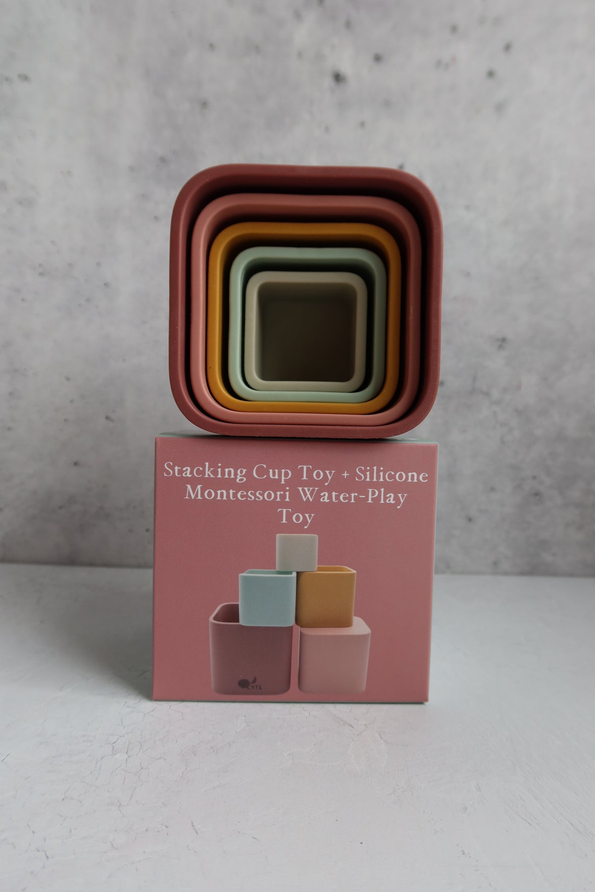 Five nested square Silicone Stacking Cups (Set of 5) balanced on top of their square packaging box.