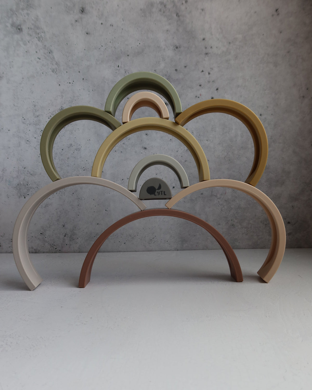 Silicone Rainbow Stacking Toy (10 pc) featuring ten arched, muted-colored silicone arches stacked in a cloud-like shape.