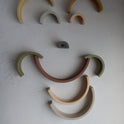 Ten pieces of the Silicone Rainbow Stacking Toy (10 pc) arranged in a smiley face pattern on a textured surface.