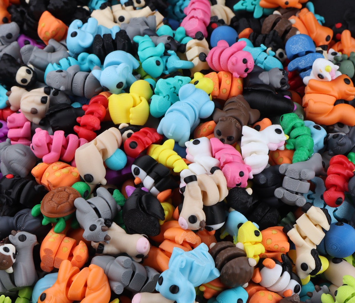 A large pile of Micro Animal Fidgets – Surprise Pack, featuring small, colorful, articulated 3D-printed animal figures in various shapes and poses, perfect as mini desk decor.