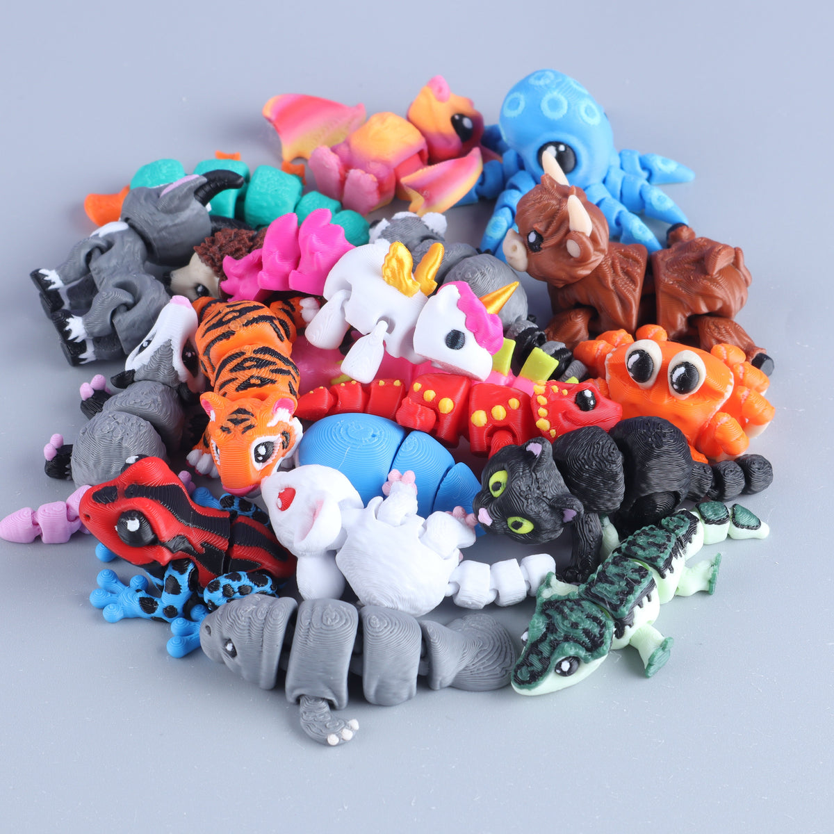 A pile of Mini Fidget Creatures – Surprise Pack toys, including a colorful articulated tiger, unicorn, blue octopus, black cat, and various 3D-printed mini animals like lizards and dragons.