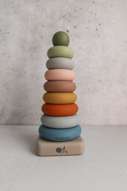 A Silicone Affirmation Ring Stacker (10 pc) featuring a stack of ten colorful silicone rings in a vertical pyramid shape, with the words I AM CONFIDENT printed on the bottom ring.