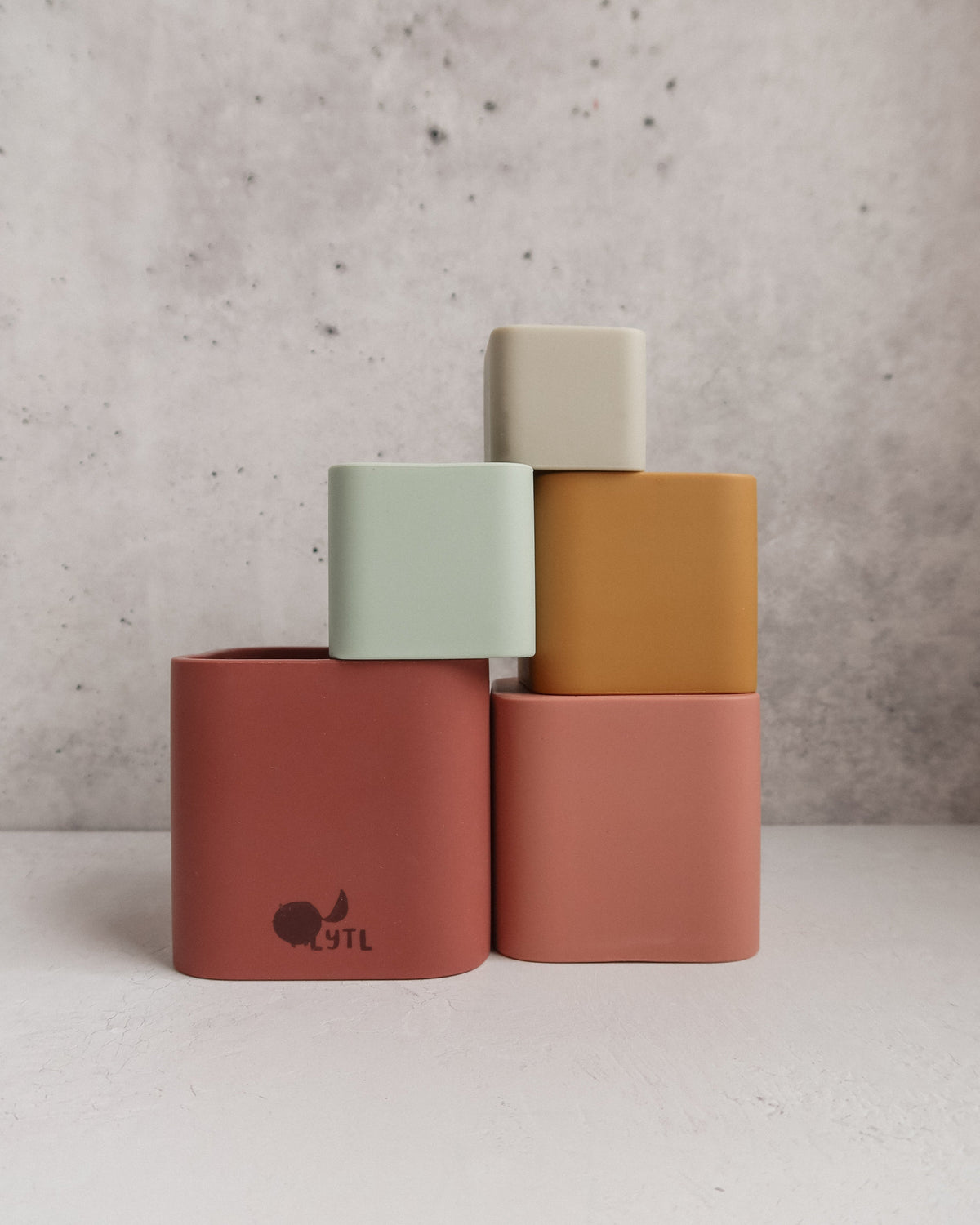Silicone Stacking Cups (Set of 5) in shades of red, pink, yellow, and green, arranged in a staggered tower.