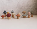 Mushroom Mix & Match Sorting Toy (24 pc) featuring twelve small wooden toys with stems and colorful, interchangeable caps in various shapes and muted tones, perfect for color sorting.