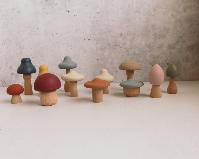 Mushroom Mix & Match Sorting Toy (24 pc) featuring twelve small wooden toys with stems and colorful, interchangeable caps in various shapes and muted tones, perfect for color sorting.