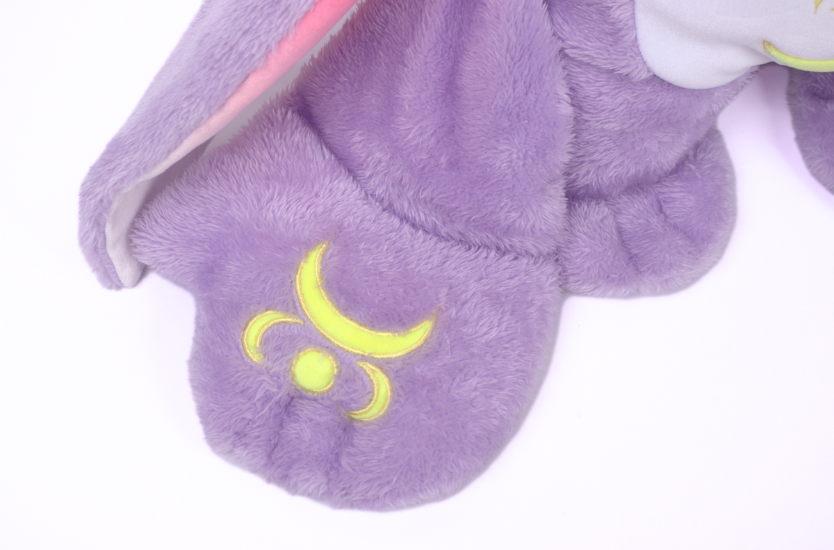 Close-up of a purple weighted plush foot from an Opal Jr. Moon Pal – 2.5 lb Kids Weighted Plush, featuring an embroidered yellow crescent moon and circle symbol.