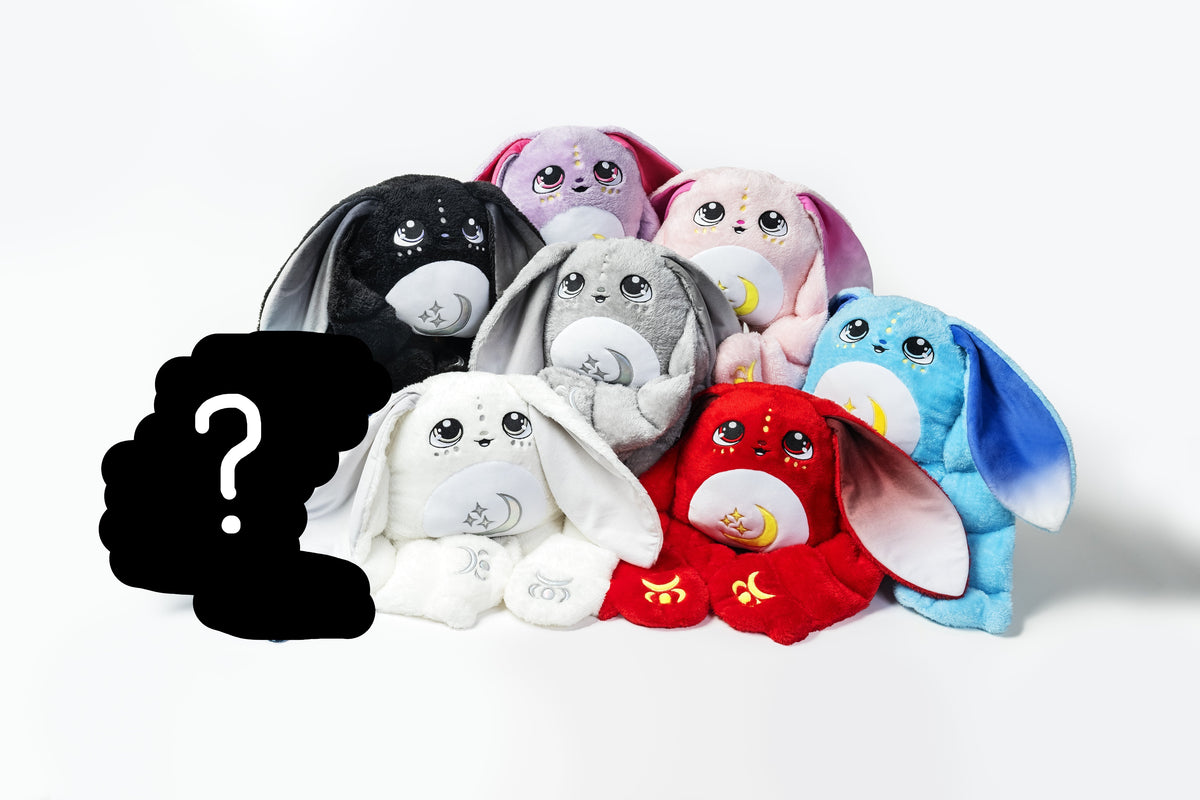 A group of seven Snowball the Moon Pal – 5 lb Weighted Plush bunnies in various colors, each with large eyes and embroidered moon and star symbols on their chests.