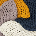 Close-up of chunky Knit Weighted Blankets in mustard yellow, navy blue, lavender, and cream—layered for a textured, cozy look. Enjoy the comfort and calming effect of a super soft weighted blanket with this inviting display.