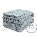 A neatly folded, thick light gray Ice Knit Weighted Blanket features a small illustration of a smiling cloud inside a thought bubble in the bottom right corner.