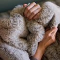 Two hands gently grasp the Snuggle Luxe Blanket in Earl Grey, showcasing its plush texture and cozy faux fur for ultimate comfort.