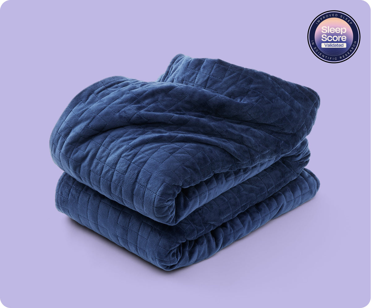 A folded navy Gravity Original Weighted Blanket (10–25 lb) with a quilted grid pattern, breathable cover, and a circular badge that reads Sleep Score Validated.