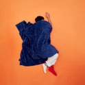 A person sleeping on an orange surface under a dark blue quilted Gravity Original Weighted Blanket (10–25 lb) with a breathable cover.