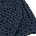 Close-up of the Knit Weighted Blanket in dark navy blue, featuring thick, soft yarn and a cozy, chunky braided texture for a warm, inviting look.