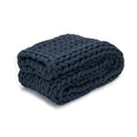 A Knit Weighted Blanket in Dusty Blue is neatly folded, showcasing its thick braided texture for a cozy, plush look.