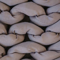 Close-up of chunky, beige strands tightly braided together, highlighting the textured and cozy appearance of the Knit Weighted Blanket.