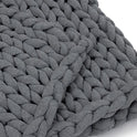 A close-up of the Knit Weighted Blanket in dark gray, highlighting its thick, chunky braided strands and soft, textured look.