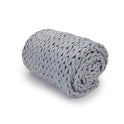 The Knit Weighted Blanket, in a thick and chunky light gray breathable knit, is rolled up neatly on a white background.