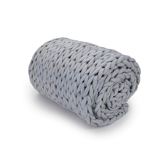 The Knit Weighted Blanket, in a thick and chunky light gray breathable knit, is rolled up neatly on a white background.