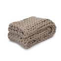The Knit Weighted Blanket in taupe is neatly folded, highlighting its chunky braided texture and providing cozy comfort.