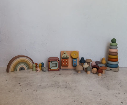 Montessori Playroom Bundle – 6 Toys featuring a rainbow stacker, nesting boxes, a shape-sorting board, silicone peg dolls, assorted mushroom figures, and a conical stacking tower.