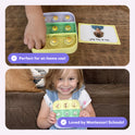 A child uses Popplers 1 + 2 Toddler Game Bundle to press emoji buttons on a silicone board next to a card showing a boy’s face, while a girl holds a board with animal pictures to build early vocabulary.