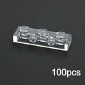 A transparent 1x3 brick from the MOC Transparent Bulk Brick Set, compatible with Lego, is displayed on a black surface. “100pcs” in white highlights this versatile clear building block collection for wall panels and house parts.