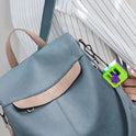 A person in a white pinstriped shirt carries a MINOCOOL light blue backpack with tan accents, featuring a Manual Gear Shifter Keychain 3D Printed Fidget Toy attached to the bag.
