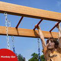 A young person hangs from a red and wooden monkey bar, part of the Wood Swing Sets for Backyard with Monkey Bar Playset. They grip two rungs as blue sky and trees fill the background. Monkey Bar text appears in the corner.