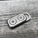 A compact, rectangular Owl Push Slider metal fidget toy with circular accents rests on a weathered wooden surface. Made in Mainland China, this adult EDC haptic slider can be spun or pushed for decompression and stress relief.