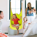 A smiling girl swings indoors in the Kids Pod Swing Seat Bag Sensory Swing Portable Hammock Chair Inflatable Swing With Cushion, while her family—man, woman with baby, and another young girl—watch and smile in a cozy, bright room.