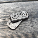 Two Owl Push Slider Fidget Toys with circular, speaker-like designs rest on a weathered wooden surface; one is stacked slightly askew atop the other.