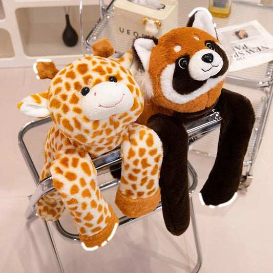 A Long Arm Animal Weighted Stuffed Animal—one a smiling giraffe, the other a red panda—are draped over the back of a metal chair in a bright room with shelves and assorted items in the background.