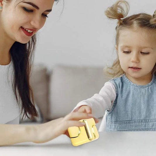 A woman and a young girl with pigtails sit together, smiling as the girl reaches for the yellow Infinity Gear Cube Spinner Antistress Toy, both engaged and focused on this fun fidget block anti-stress game.
