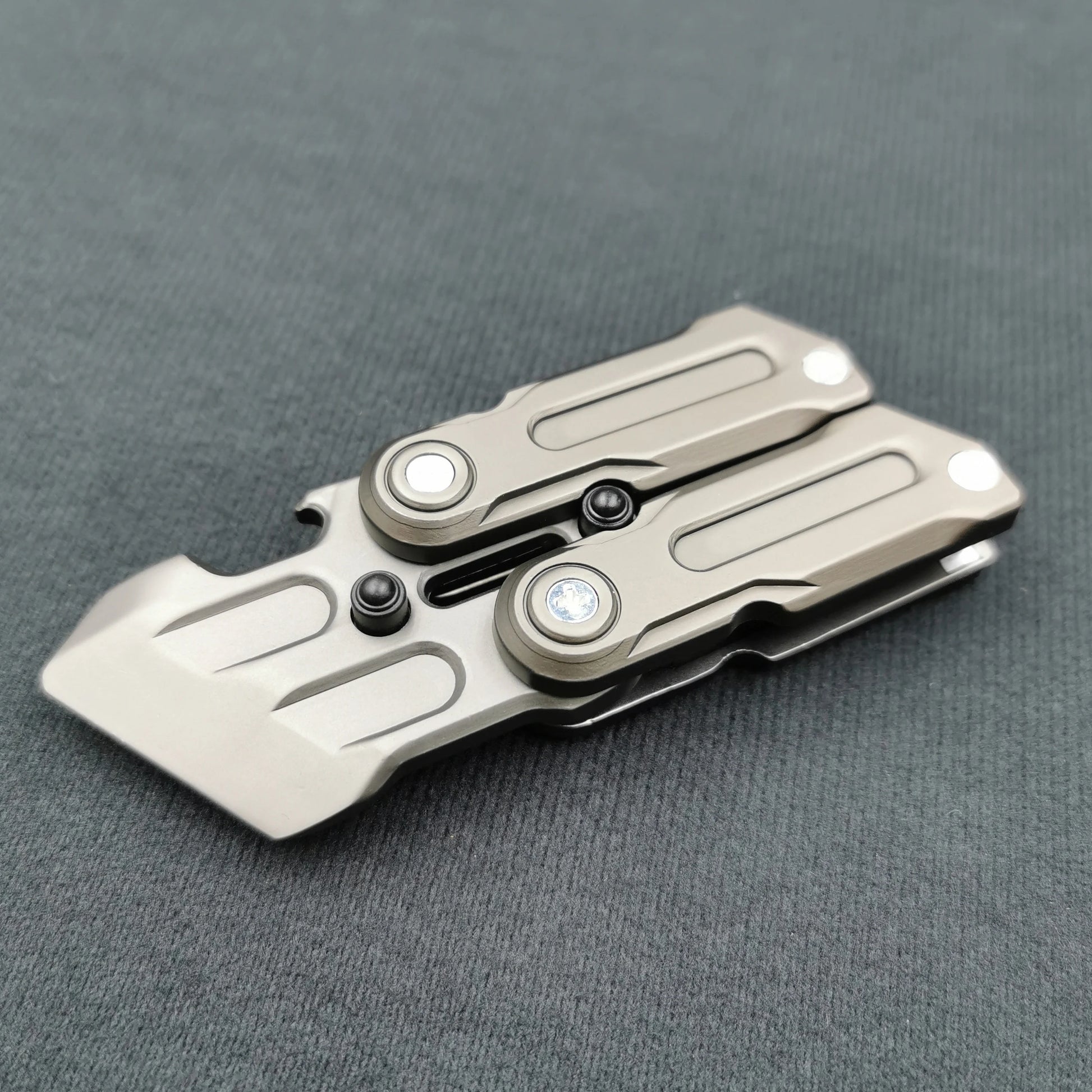 A gray Fidget Magnetic Coin EDC Adult Decompression Toy, shaped like a multifunctional crowbar fidget slider spinner, with geometric design and two pivot screws, rests on a textured gray surface as an anxiety and stress relief gift.