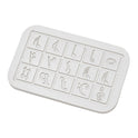 A white rectangular Fidget Clicker from Mainland China with 15 embossed boxes, each showing a unique symbol, on a chemical-free surface. Suitable for ages 6-12. Features magnetic, detachable alloy piano keys for tactile play.