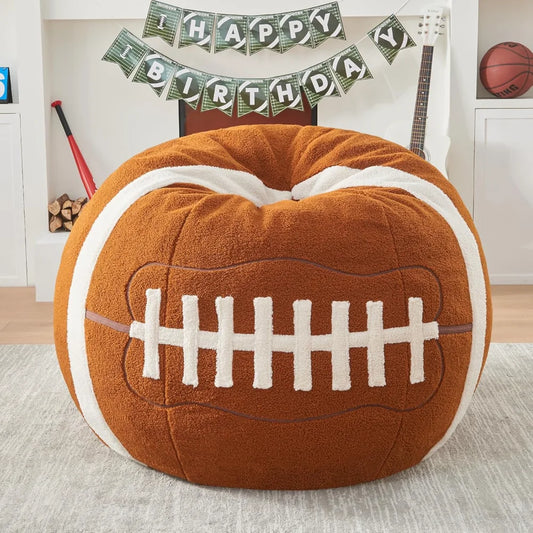 The Sports Football Bean Bag Chair for Adults and Kids in Football color, crafted with ultra-soft sherpa plush, sits in a sports-themed living room decorated with a Happy Birthday banner, guitar, bat, basketball, and stacked firewood.