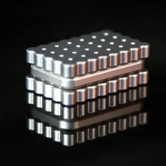 A Biscuits Fidget Slider, a rectangular metallic executive desk toy with a cartoon biscuit design and textured surface, sits on a reflective black surface—this rustproof sensory toy for kids originates from China.