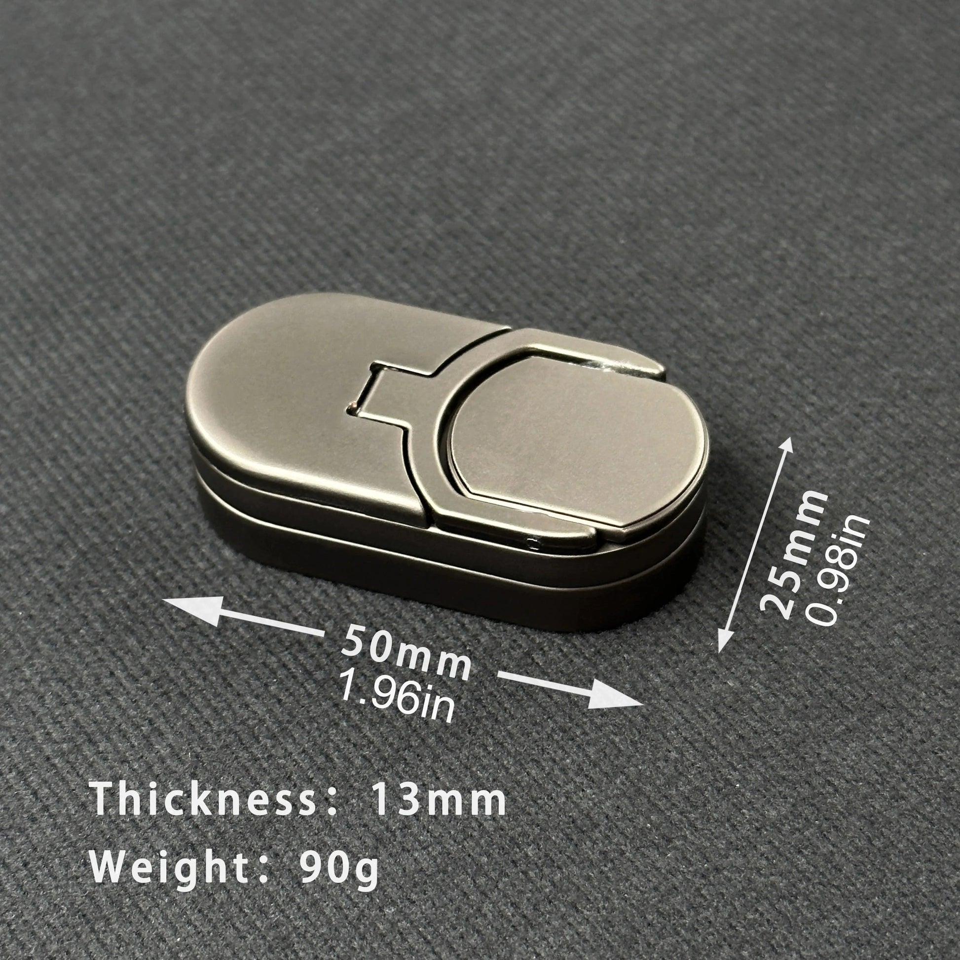 The Target Push Slider Fidget Slider Toy Metal EDC rests on a textured surface, featuring rounded edges, 50mm (1.97in) by 25mm (0.98in) size, 13mm thickness, and weighing 90g. Arrows indicate its length and width in mm and inches.