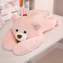 A Long Arm Animal Weighted Stuffed Bear Plush, soft and fluffy in Bear color, lies on its stomach on a white desk among stationery and a cup—perfect as a cute cushion pillow for your workspace.