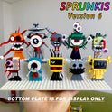 A hand holds a red baseplate featuring eight playful LEGO robots from the New Moc Incredibox Sprunki Building Blocks Set Horror Anime Music Game Bricks Toy, each with distinct faces. “BOTTOM PLATE IS FOR DISPLAY ONLY” is below.