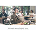 A woman wearing WH-CH720N Wireless Bluetooth Headphones with noise canceling sits at a café, eyes closed and smiling as she enjoys music. Spanish text highlights features like 35H battery, quick charge, and built-in mic. Others are in the background.
