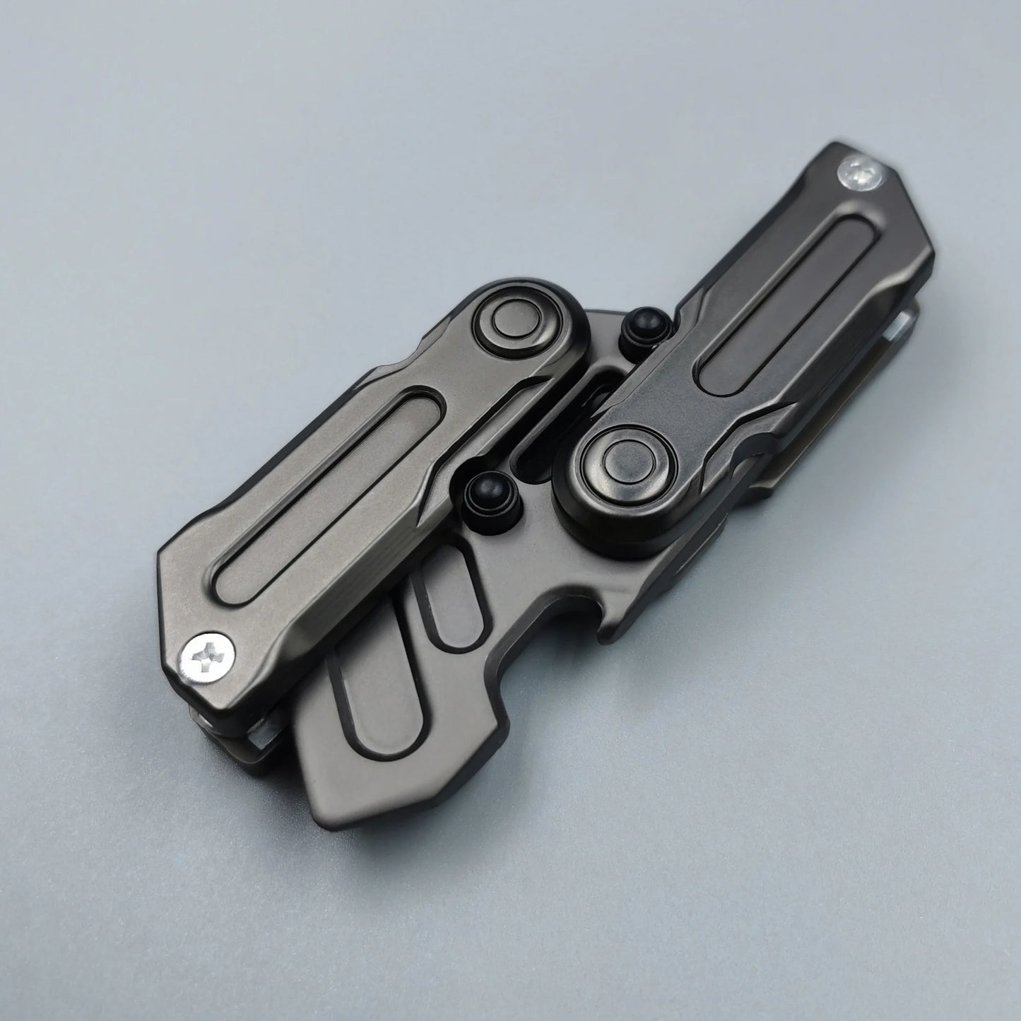 A Fidget Magnetic Coin EDC Adult Decompression Toy, a multifunctional crowbar fidget slider spinner for anxiety and stress relief, lies closed on a light gray surface, displaying quality metal construction and CE Certification.