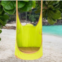 A Kids Pod Swing Seat Bag Sensory Swing Portable Hammock Chair Inflatable Swing with Cushion hangs from a tree on a sandy beach, surrounded by lush green leaves and turquoise water in the background.