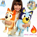 A smiling young girl holds 17cm-40cm Bluey and Bingo Family Plush Toys—soft cartoon dog dolls in orange and blue—against a light background. Perfect birthday or Christmas gifts, with show branding visible in the corners.