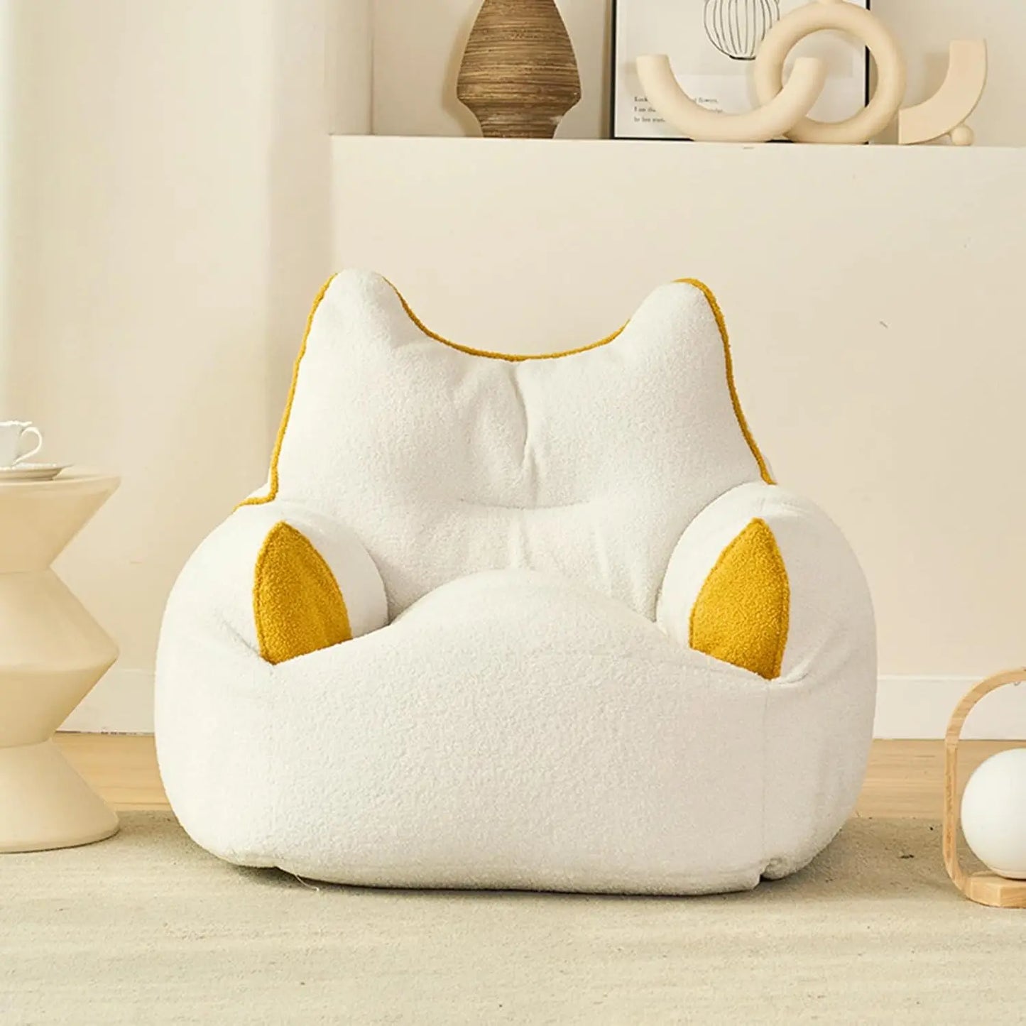 A beige Premium Teddy Velvet Bean Bag Sofa Cover for Indoor Lounging, shaped like a cat, adds comfort and style as plush toy storage or seating in a cozy, modern room with minimalist decor.