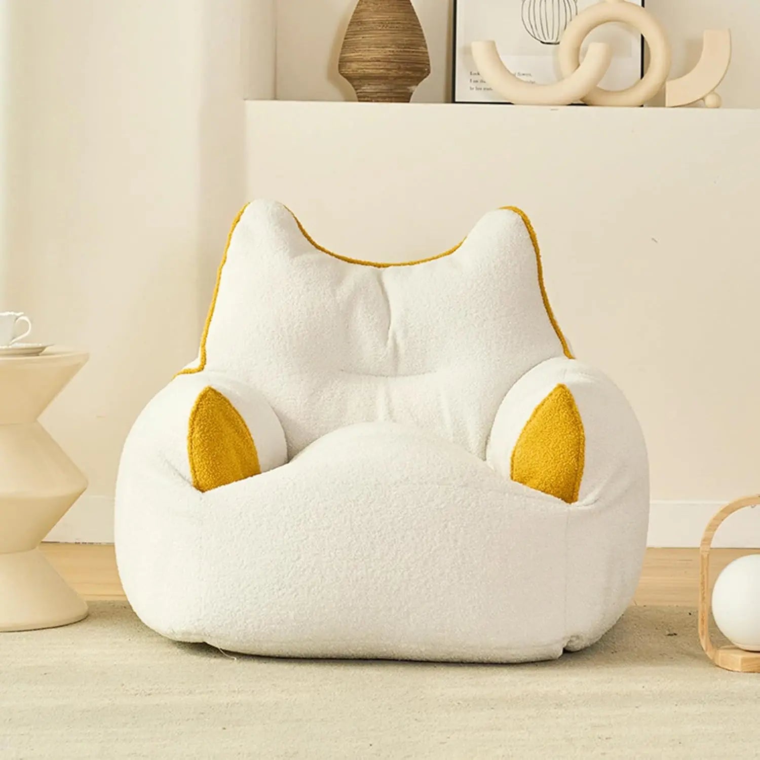 A beige Premium Teddy Velvet Bean Bag Sofa Cover for Indoor Lounging, shaped like a cat, adds comfort and style as plush toy storage or seating in a cozy, modern room with minimalist decor.