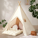 Cream-colored teepee play tent with a Thick Padded Play Cushion, decorative pillows, and a small woven house-shaped basket.