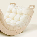 A Thick Padded Play Cushion in a tufted cream color, fitted onto a curved wooden rocker with handles on both ends.