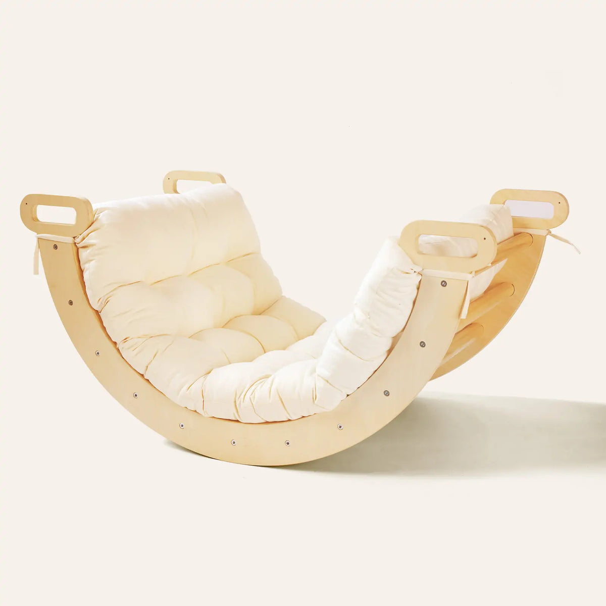 A curved wooden rocker with handles and a Thick Padded Play Cushion in cream.